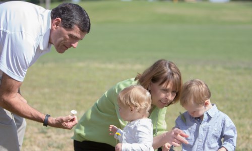 family on walk outside picking flowers